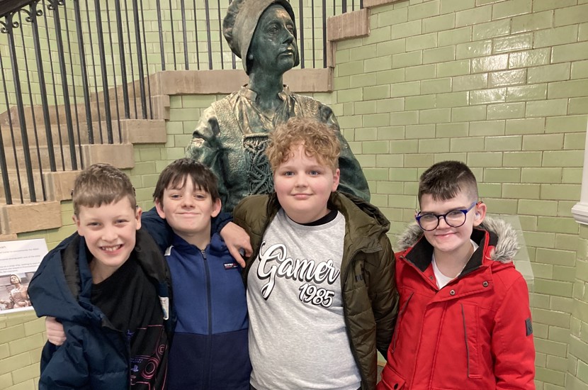Four Dickson House residents in front of a bronze statue at DGLAM